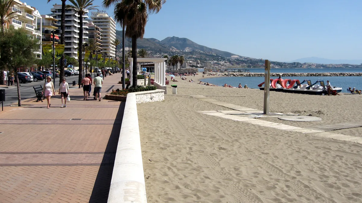 Paseo marítimo de Fuengirola con palmeras, paseantes y la playa al fondo
