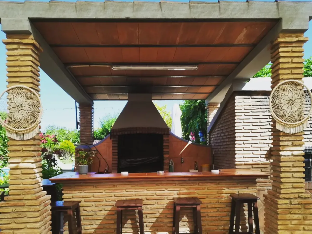 Barra de la barbacoa de obra de Villa Meli, con taburetes y atrapasueños en las columnas